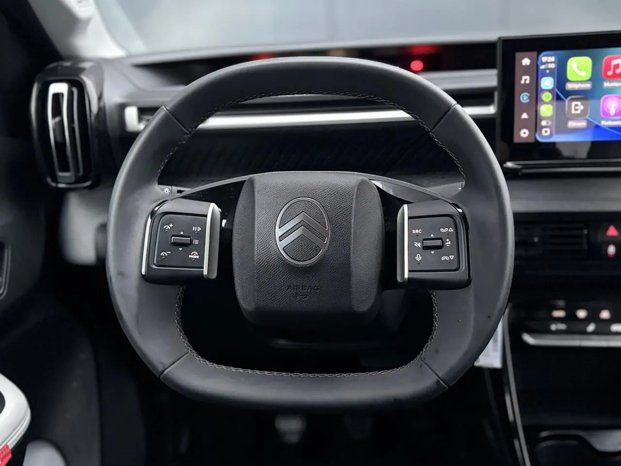 Vue frontale du volant noir de la Citroën C3 2025 avec commandes intégrées et écran tactile multimédia en arrière-plan.