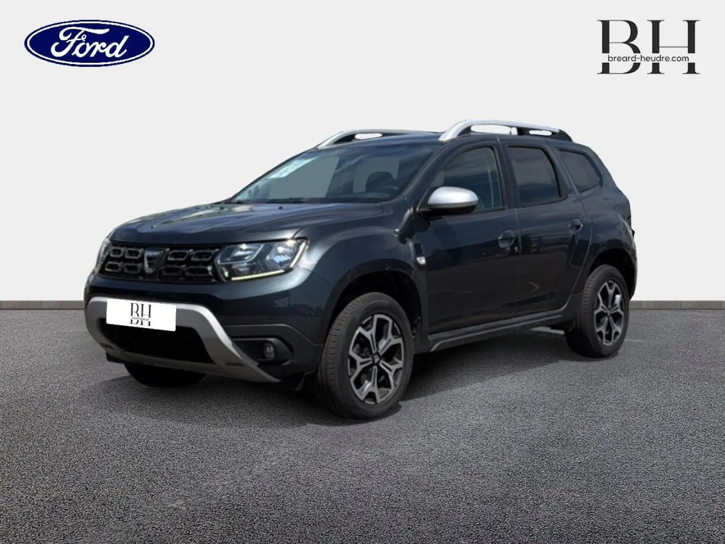 SUV Dacia Duster gris Comète métallisé vu en 3/4 avant droit avec barres de toit et jantes alu noires.