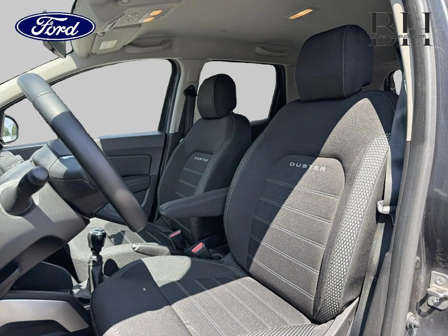 Intérieur du Dacia Duster 2020, vue côté conducteur, sièges noirs avec logo Duster brodé, volant multifonction visible.