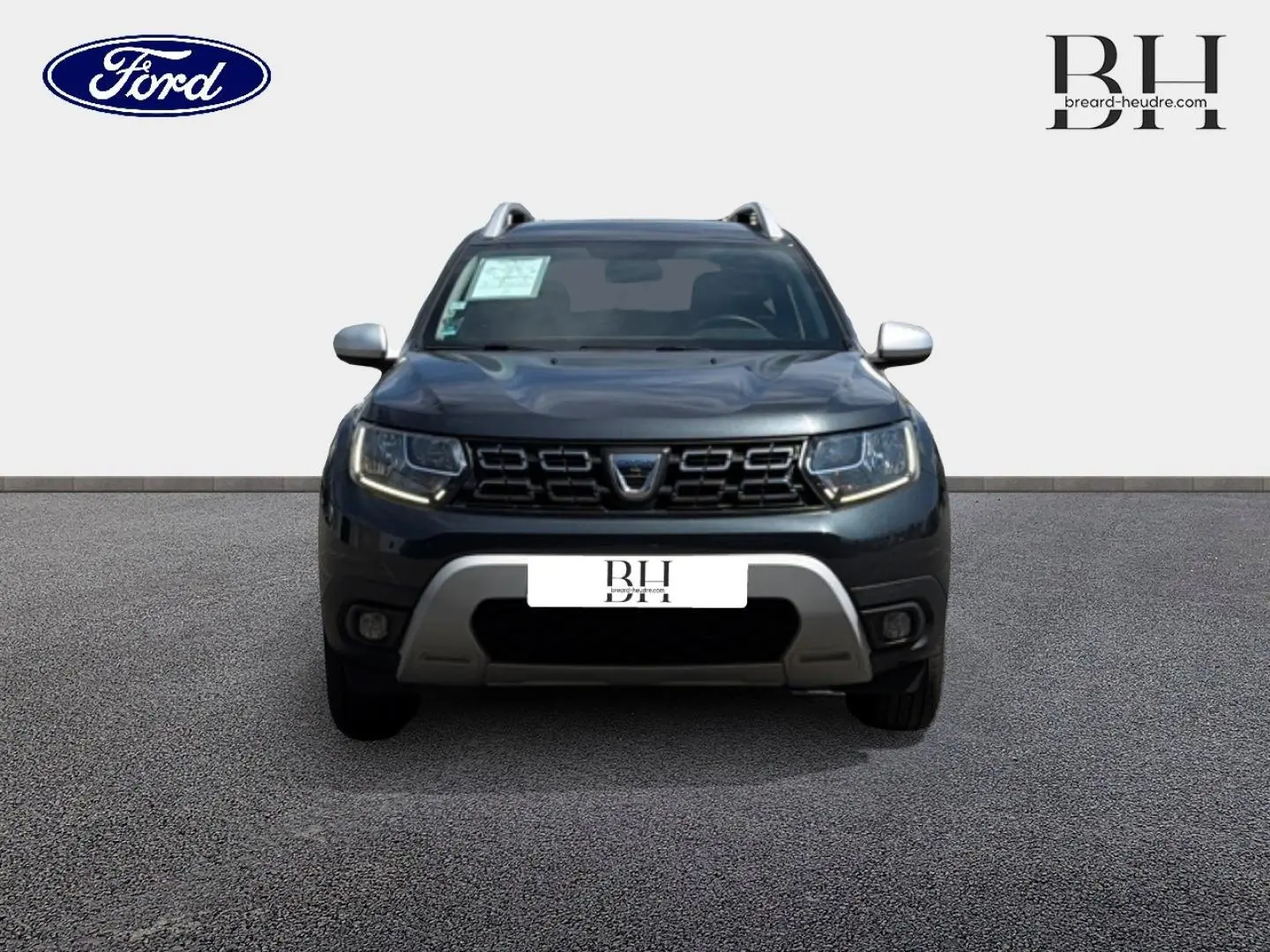 Vue avant du Dacia Duster gris Comète métallisé avec calandre noire et protections argentées sur pare-chocs.