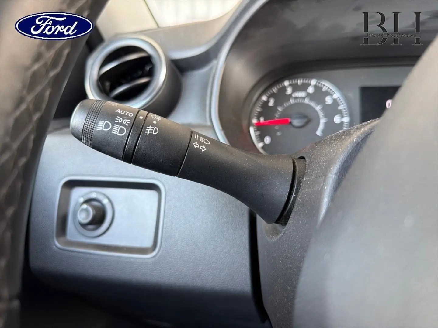 Manette de commande des phares en gros plan à gauche du volant, intérieur noir d’un véhicule Ford.