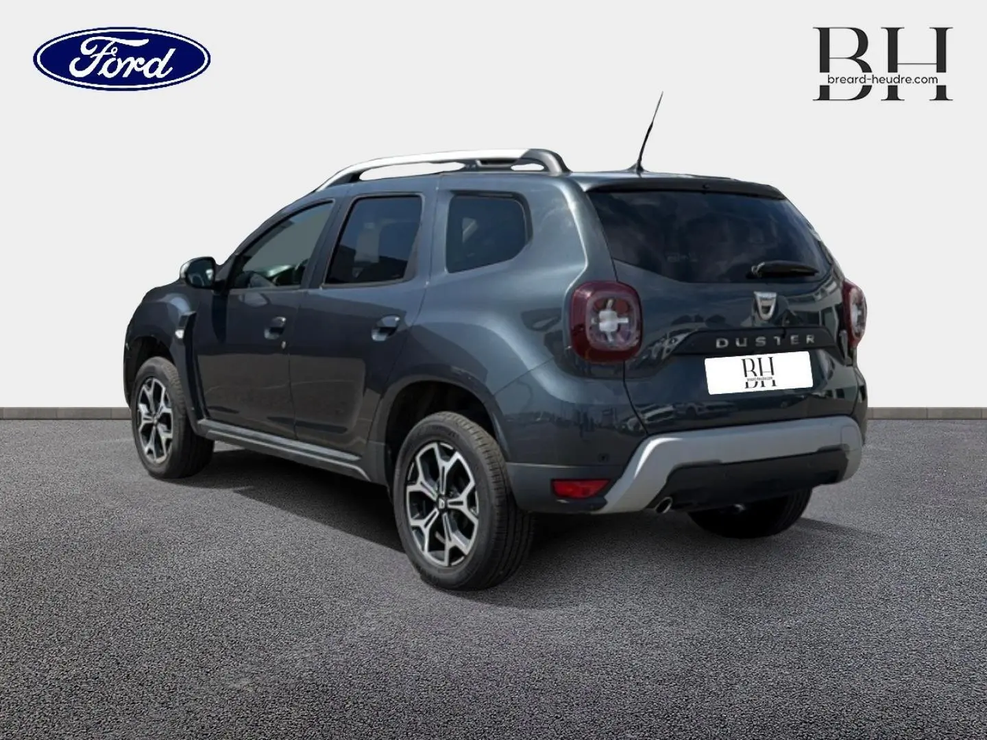 Vue 3/4 arrière droite du Dacia Duster gris Comète métallisé avec barres de toit et jantes alu distinctives.