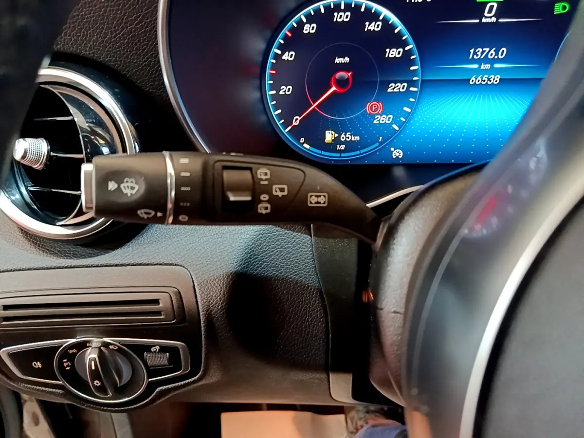 Gros plan sur le combiné d'instruments numérique bleu et le commodo de phares dans l'habitacle gris foncé d'une Mercedes GLC 300 E AMG Line 2021.