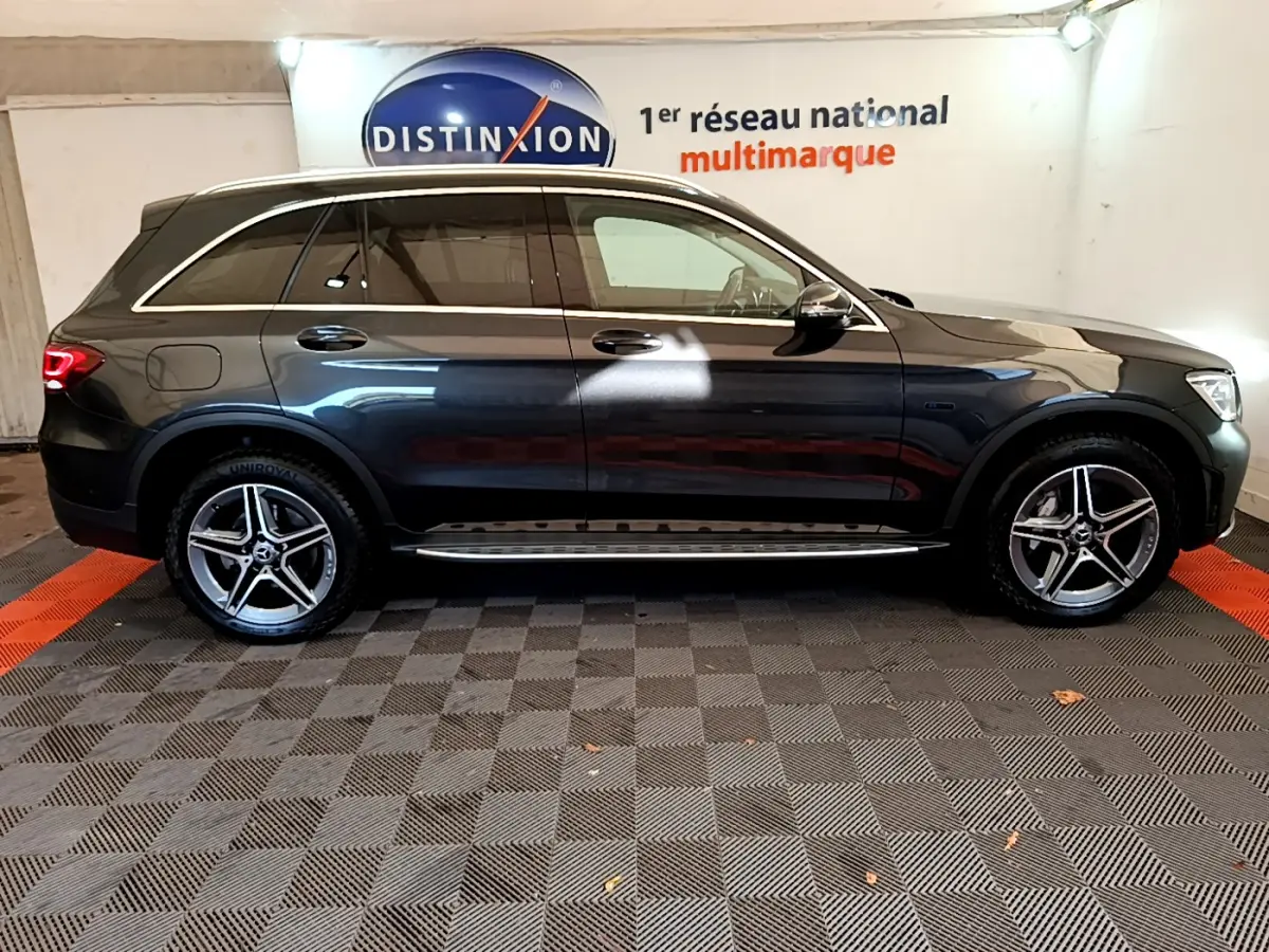 Vue latérale droite d'un Mercedes GLC 300 E AMG Line gris foncé avec jantes alliage et rails de toit chromés.