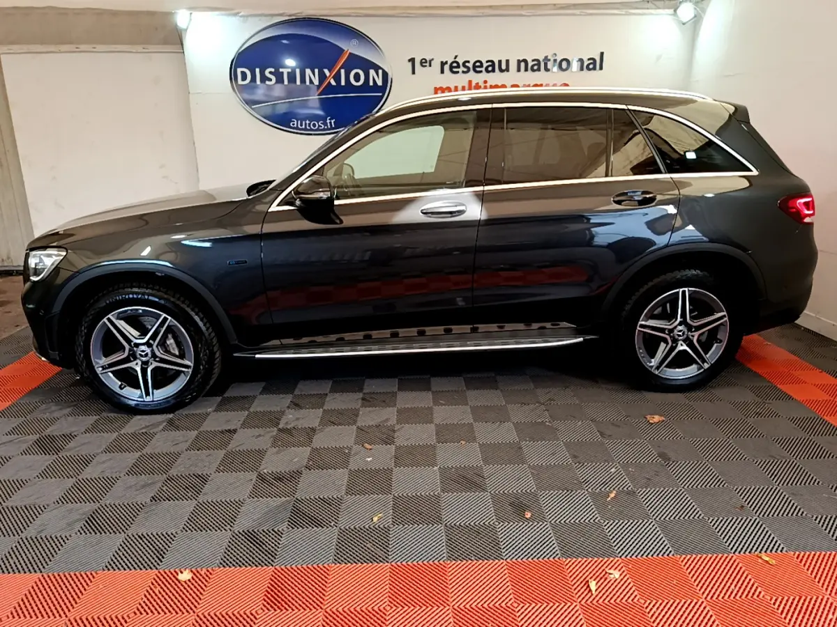 Profil droit d'un Mercedes GLC 300 E AMG Line gris foncé avec jantes alliage et vitres teintées en intérieur showroom.