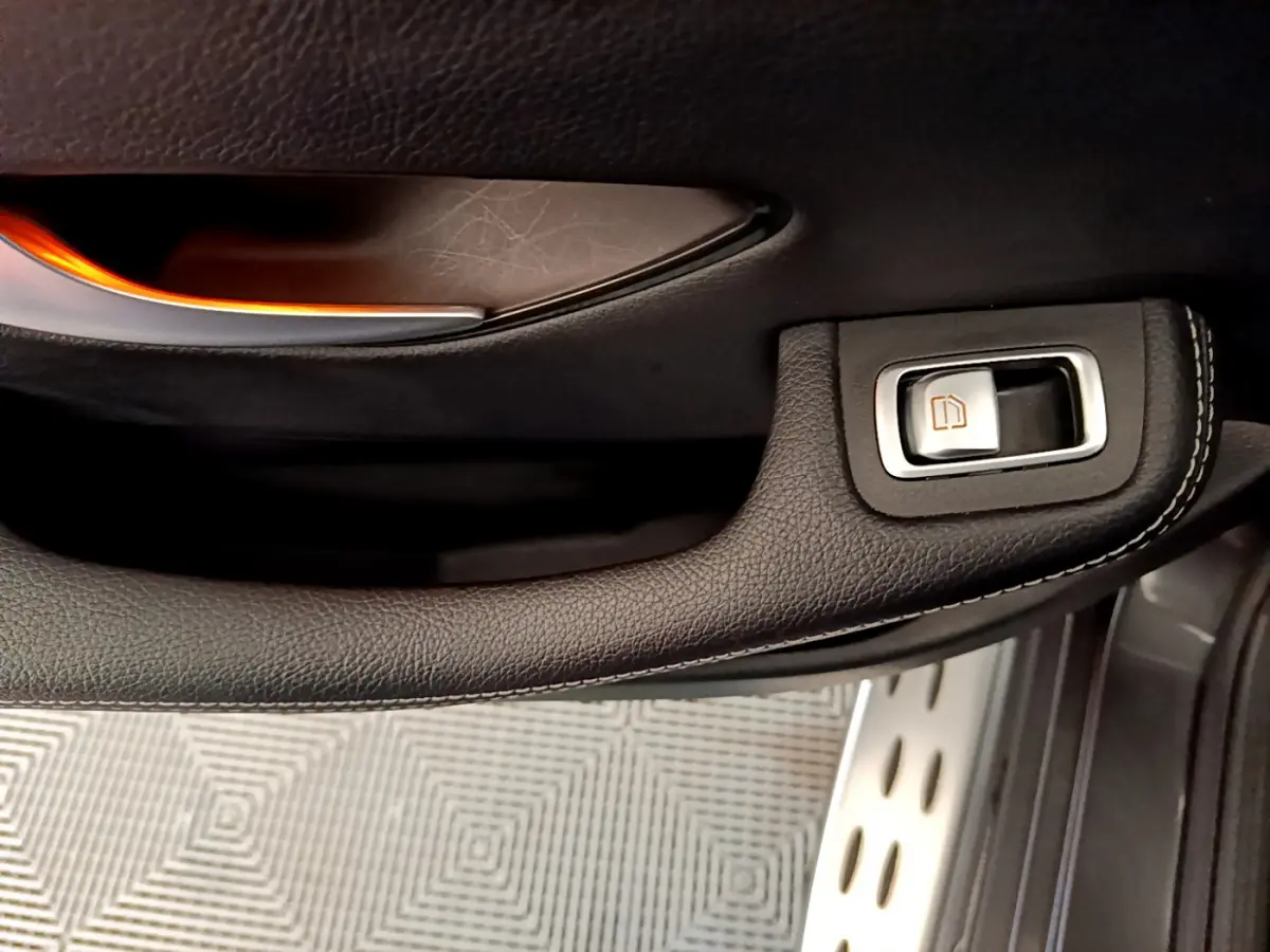 Gros plan sur la poignée de porte intérieure en cuir noir avec bouton de lève-vitre du Mercedes GLC 300 E AMG Line.