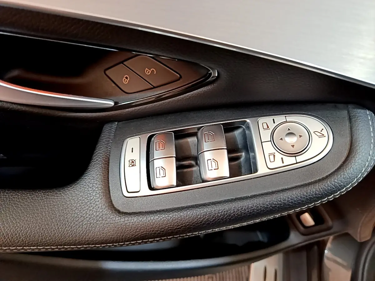 Gros plan sur les commandes de lève-vitres et rétroviseurs côté conducteur d'un Mercedes GLC 300 E AMG Line gris foncé.