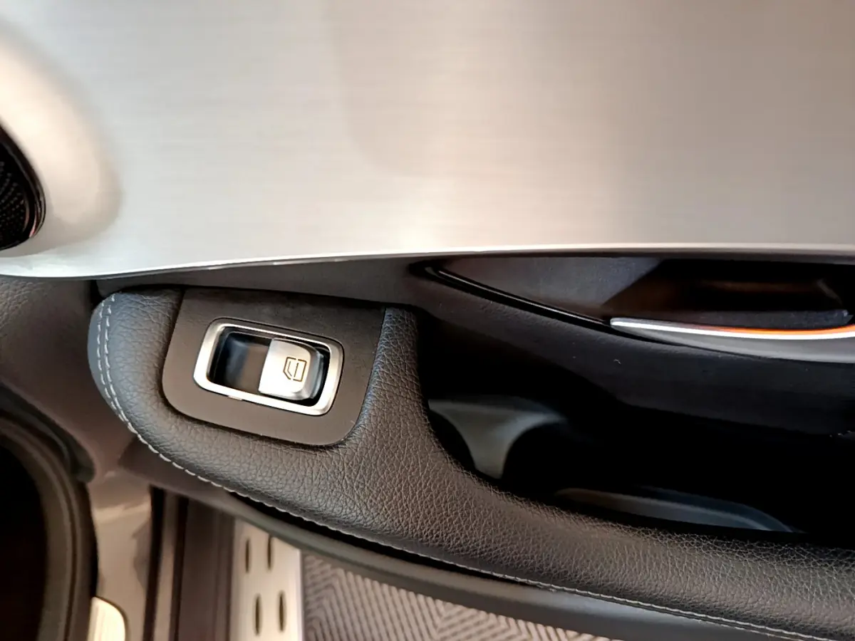Gros plan sur la commande de lève-vitre côté conducteur en cuir noir et insert aluminium du Mercedes GLC 300 E AMG Line 2021.
