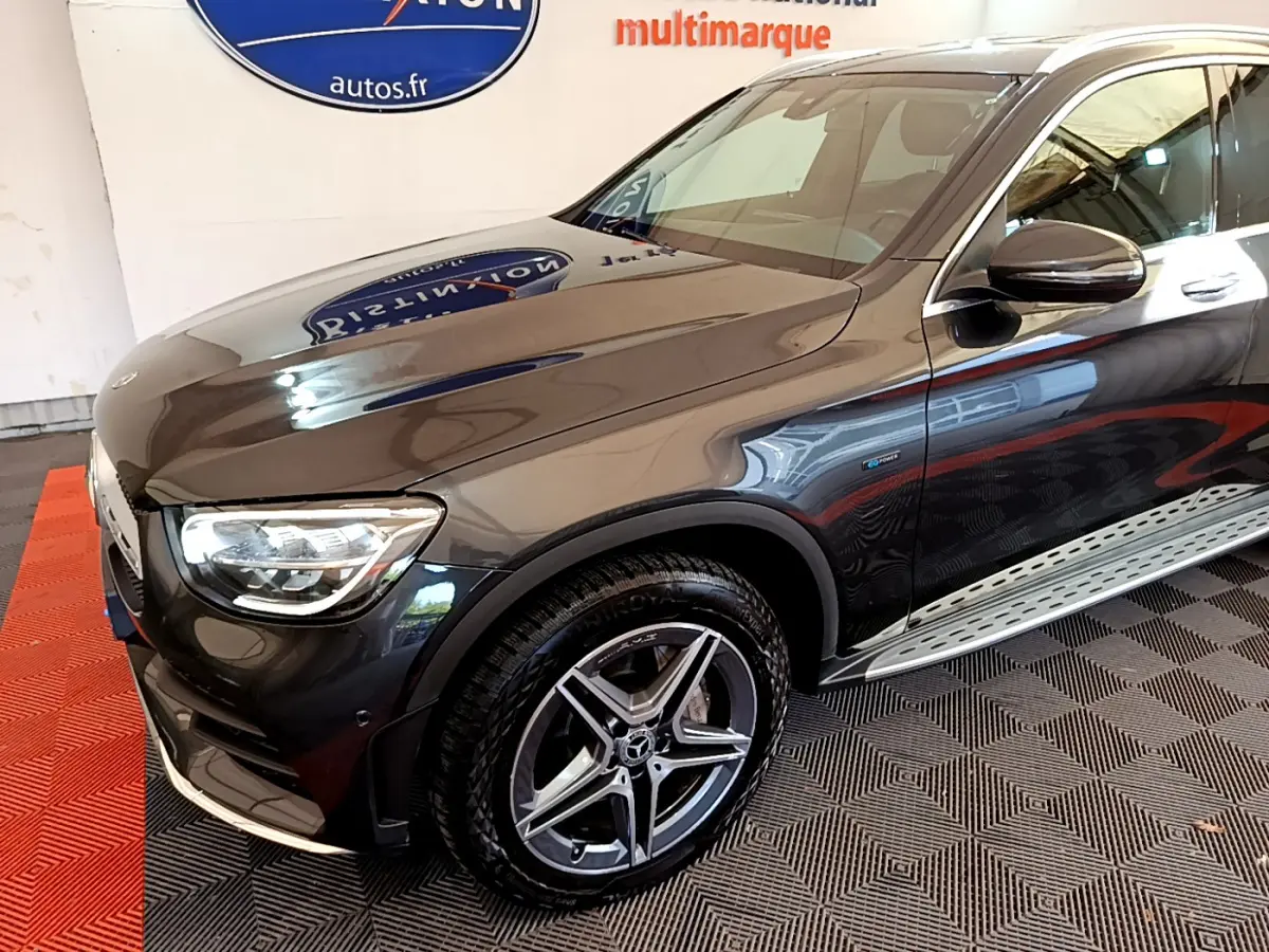 Vue 3/4 avant droit d'un Mercedes GLC 300 E AMG Line gris foncé avec jantes alliage et badge hybride visible sur la portière.