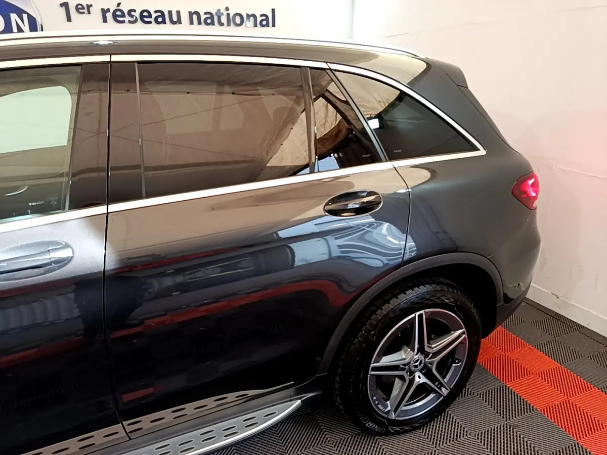 Vue côté droit arrière d'un Mercedes GLC 300 E AMG Line gris foncé avec jante alliage et feux LED allumés.