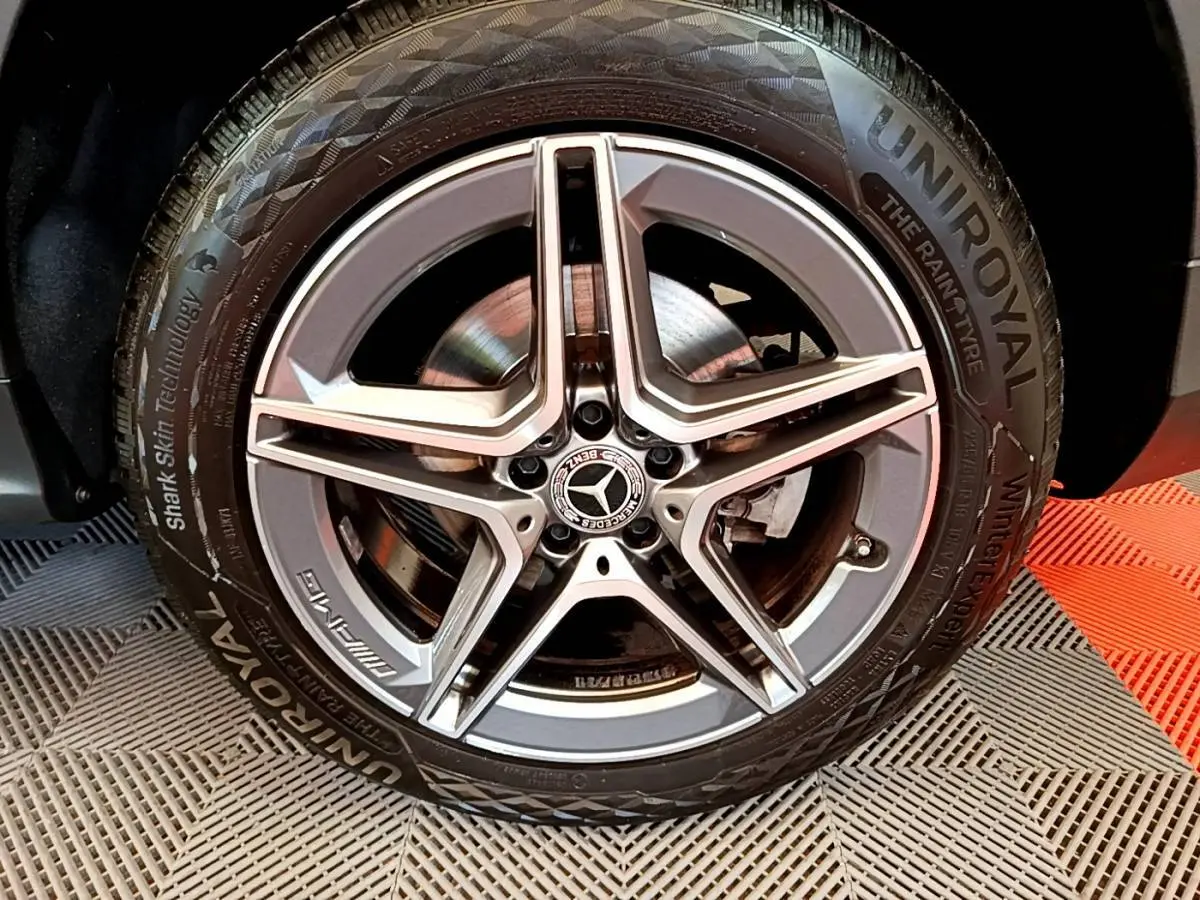 Gros plan sur la jante AMG étoile argentée et pneu Uniroyal d'un Mercedes GLC 300 E hybride gris foncé.