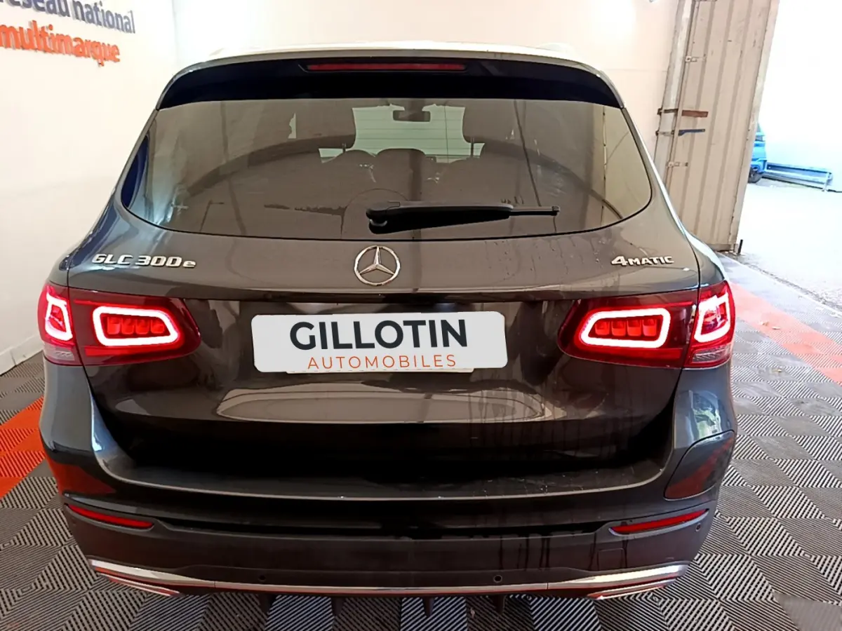 Vue arrière d'un Mercedes GLC 300 e AMG Line gris foncé avec feux LED allumés et logo 4MATIC visible