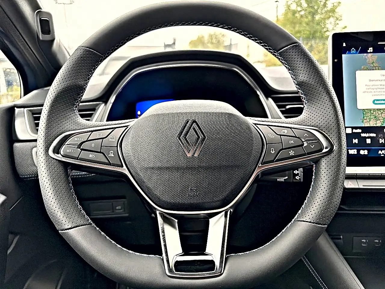 Vue rapprochée du volant multifonction noir de la Renault Symbioz 2026 avec écran tactile en arrière-plan.