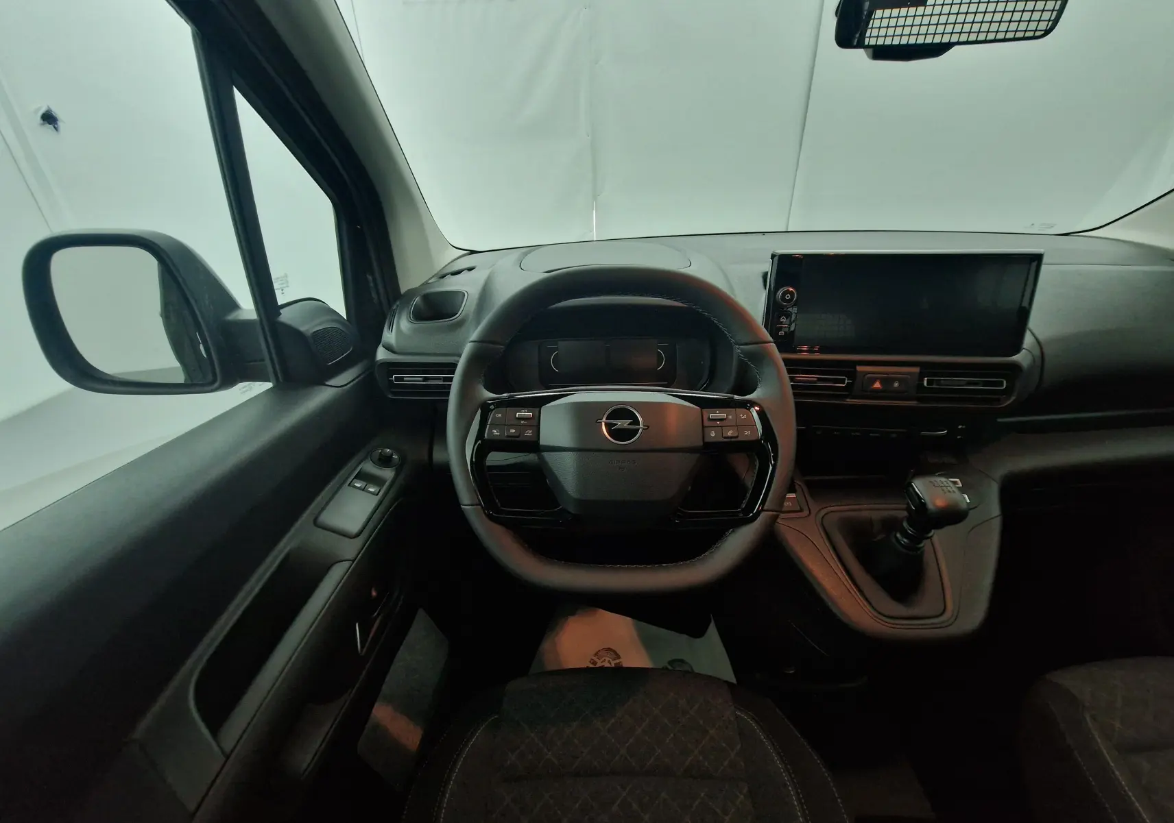 Intérieur Opel Combo Life 2025, vue du poste de conduite avec volant multifonction, écran tactile et boîte manuelle noire.