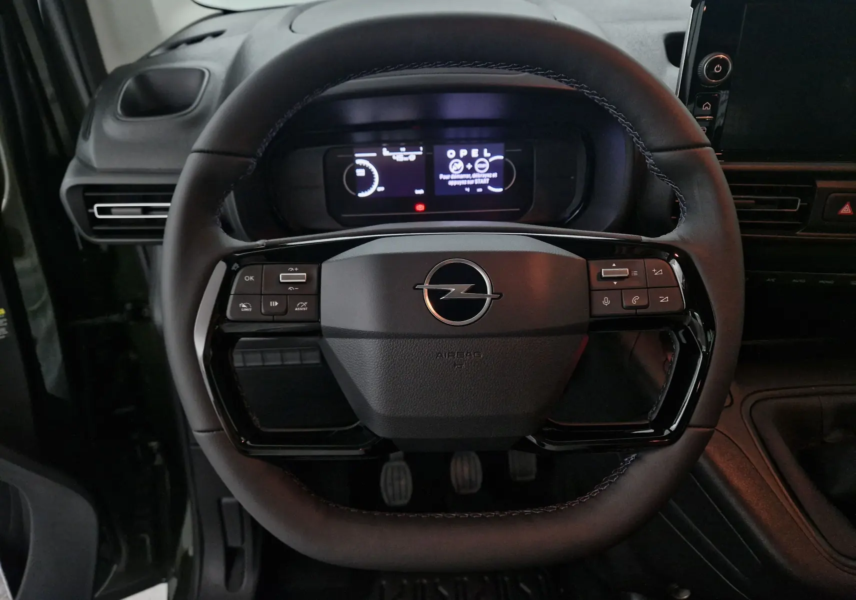 Vue rapprochée du volant noir de l'Opel Combo Life 2025 avec commandes intégrées et tableau de bord numérique.