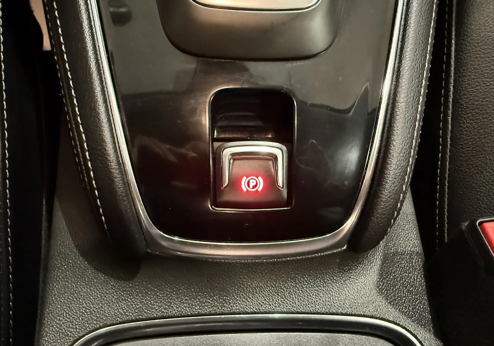 Gros plan sur le bouton de frein à main électronique rouge dans la console centrale noire de l’Opel Grandland X hybride 2021.