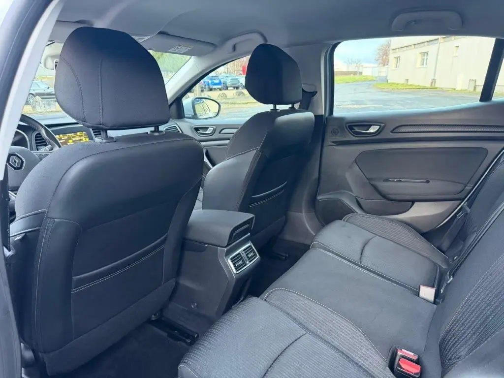 Vue intérieure arrière côté droit de la Renault Mégane Business gris alu, montrant les sièges et la console centrale avec aérateurs.