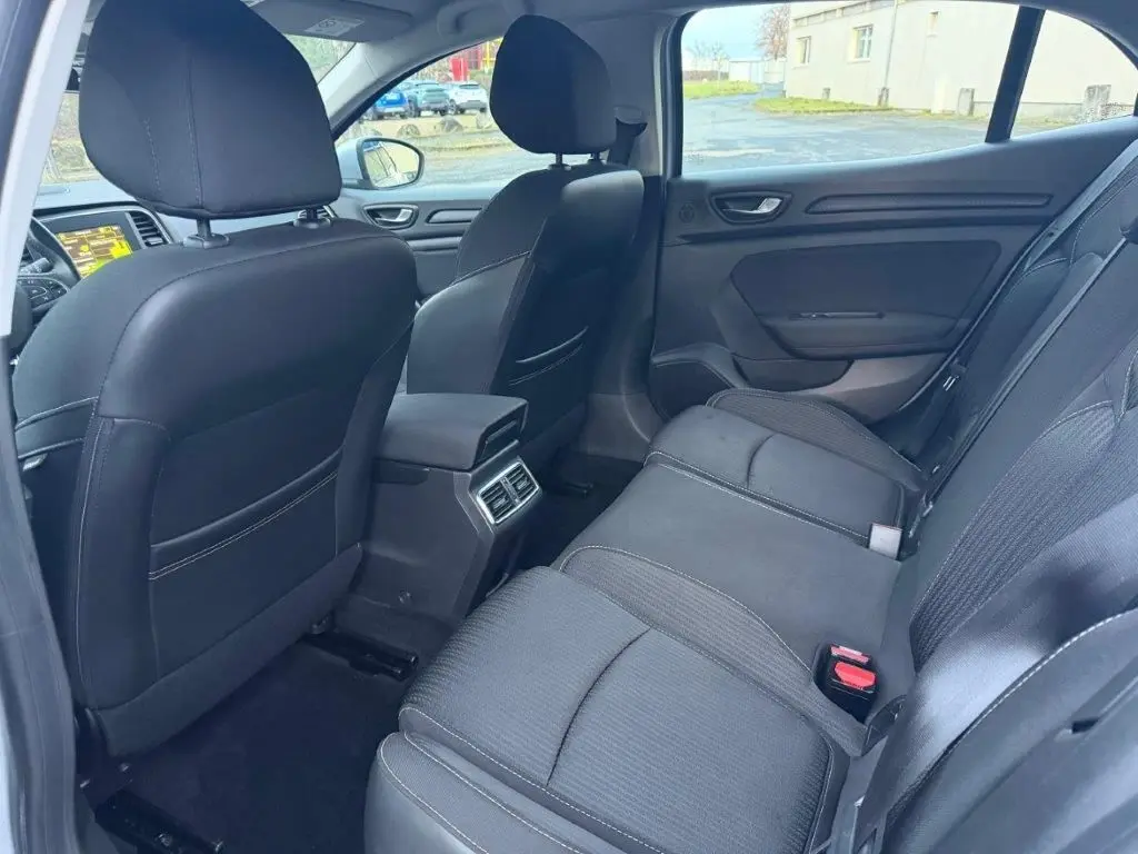 Vue intérieure arrière côté droit de la Renault Mégane Business gris alu, montrant les sièges noirs et les aérateurs centraux.