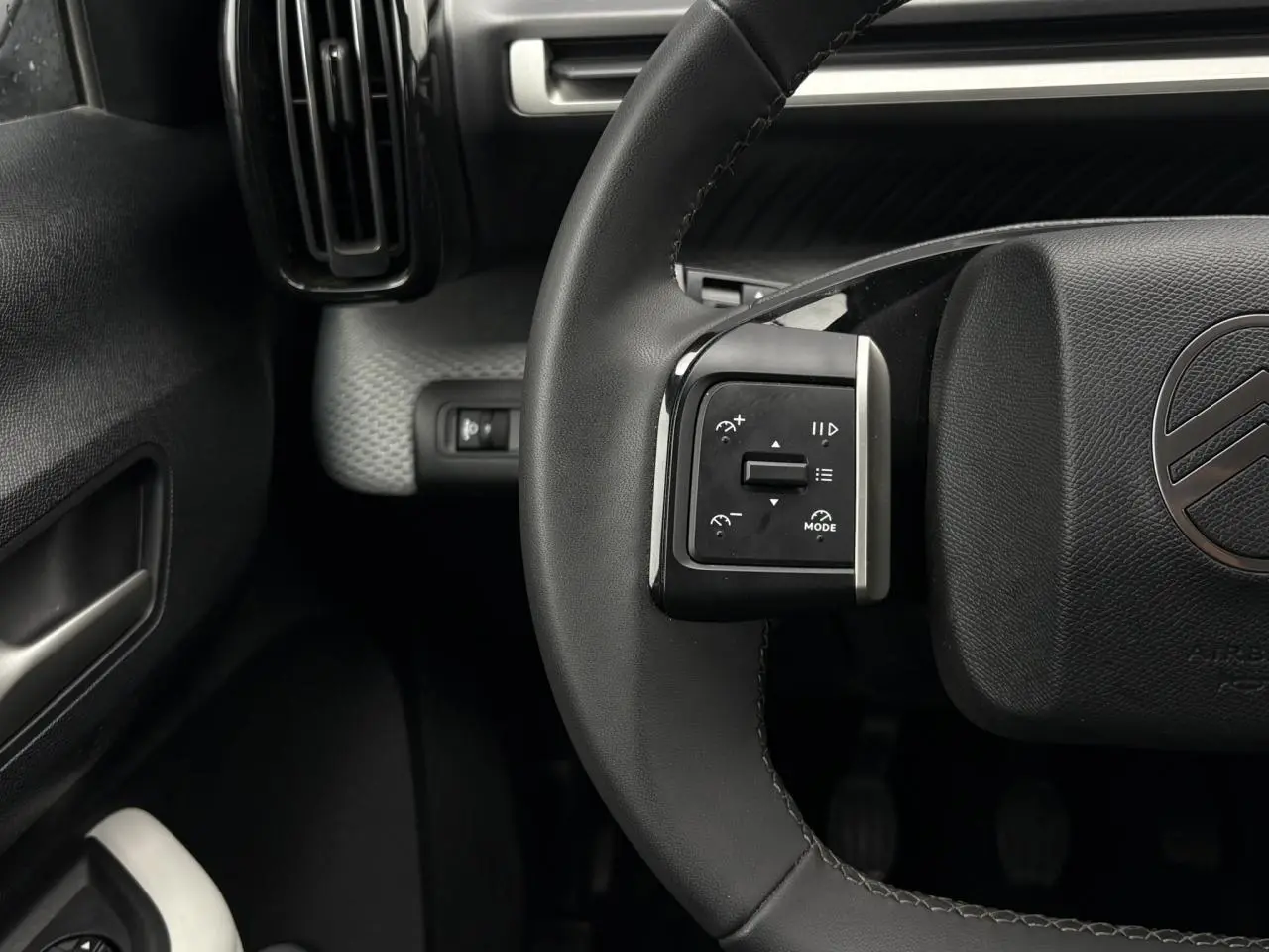 Gros plan sur le volant noir de la Citroën C3 Turbo 100 Max 2025, avec commandes intégrées à gauche et logo central.