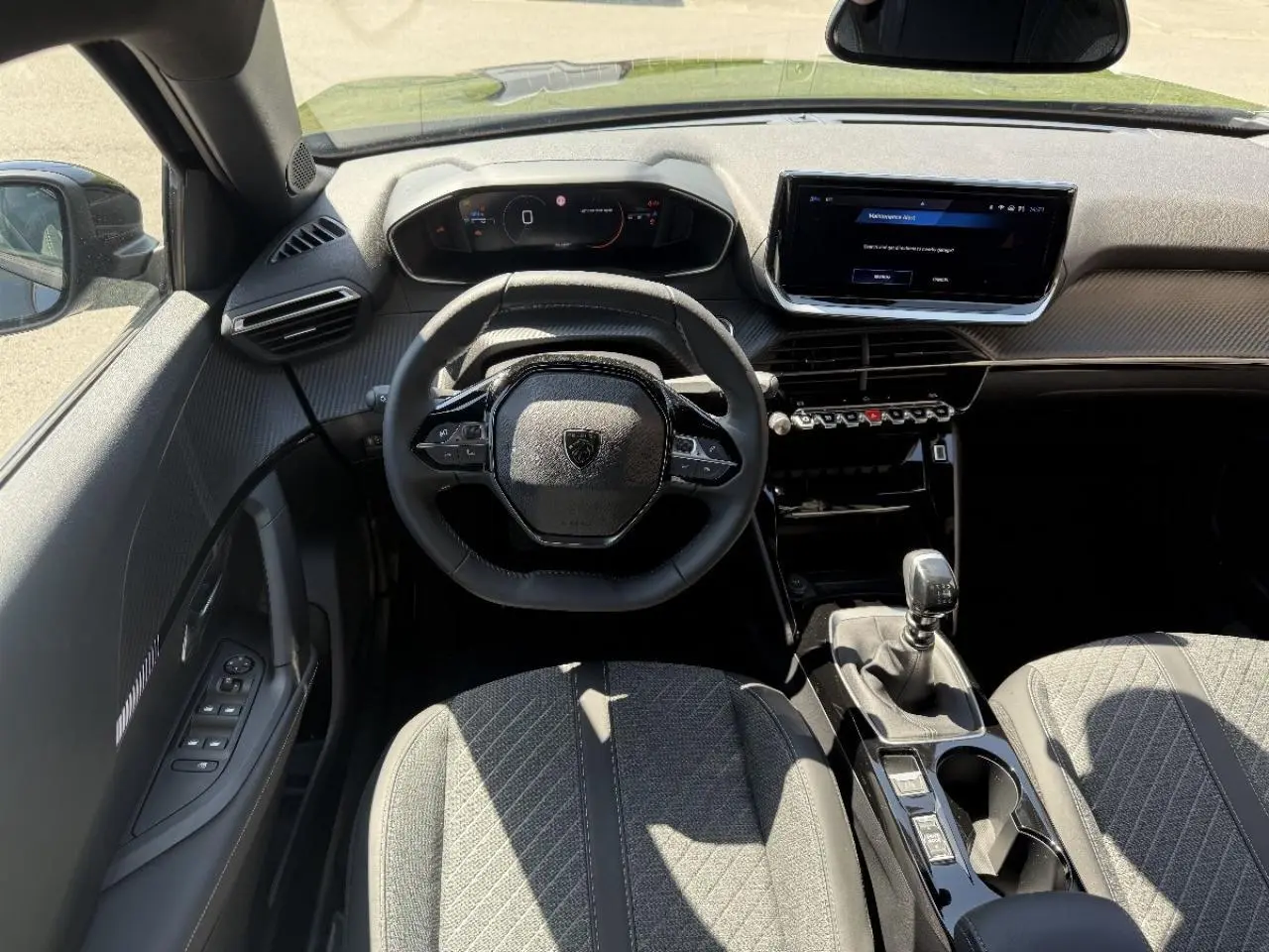 Vue intérieure avant du Peugeot 2008 2024 noir perla, montrant le volant compact, tableau de bord numérique et levier de vitesse manuel.