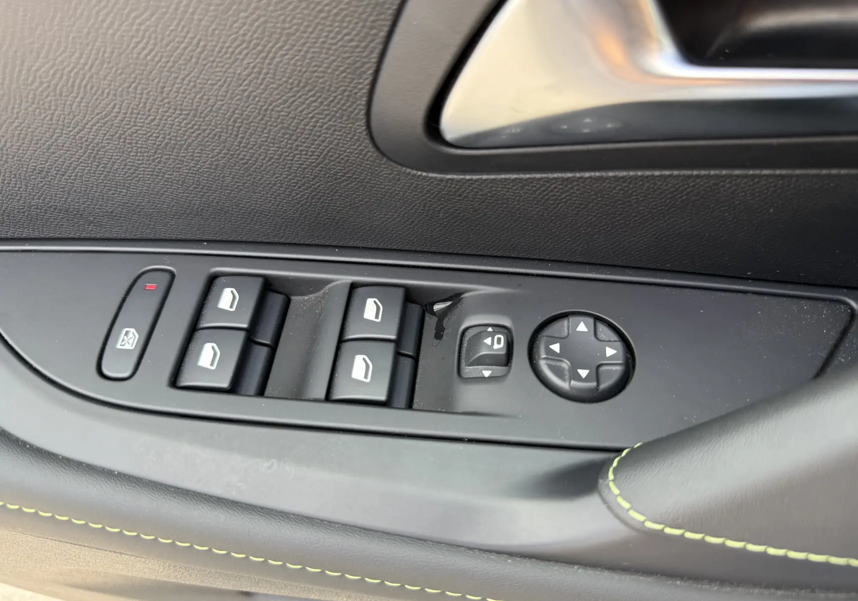 Gros plan sur les commandes de lève-vitres et réglage des rétroviseurs côté gauche d'une Peugeot 208 Hybrid 145 GT gris Artense.