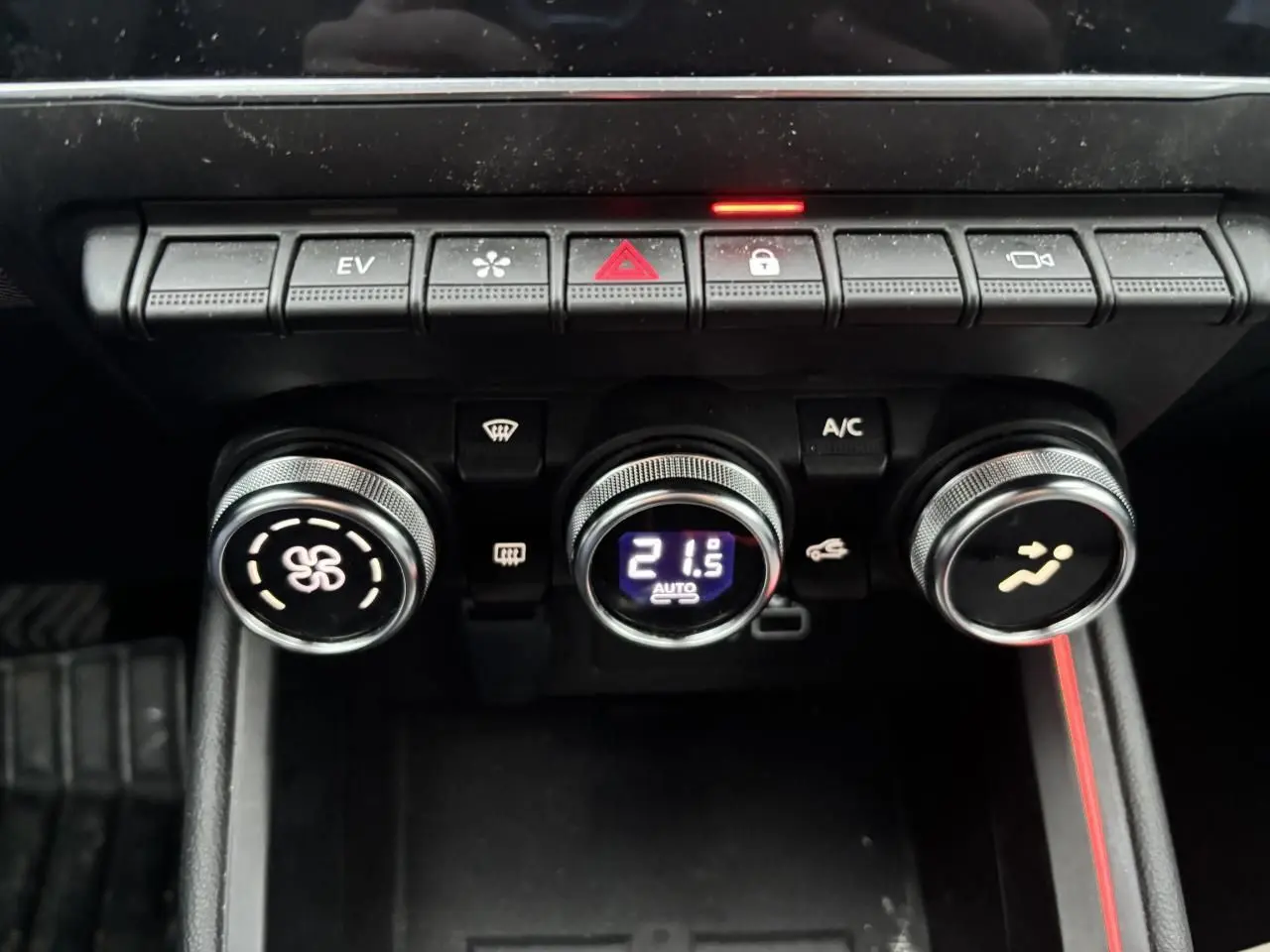Vue rapprochée des commandes de climatisation et des boutons de fonction sur la console centrale de la Renault Clio rouge flamme.
