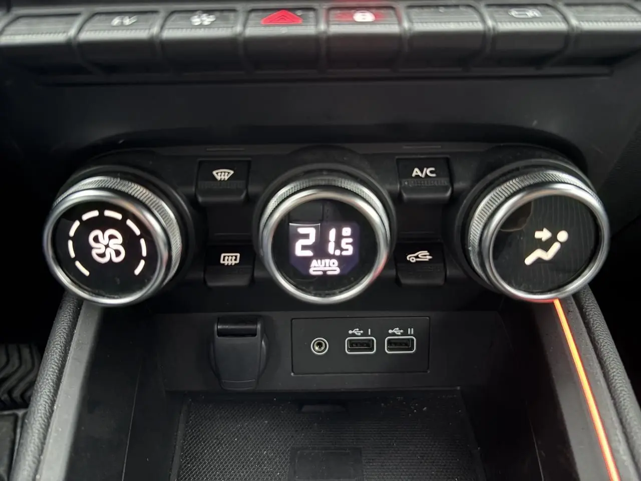 Gros plan sur les commandes de climatisation avec affichage digital et ports USB de la Renault Clio V rouge flamme.