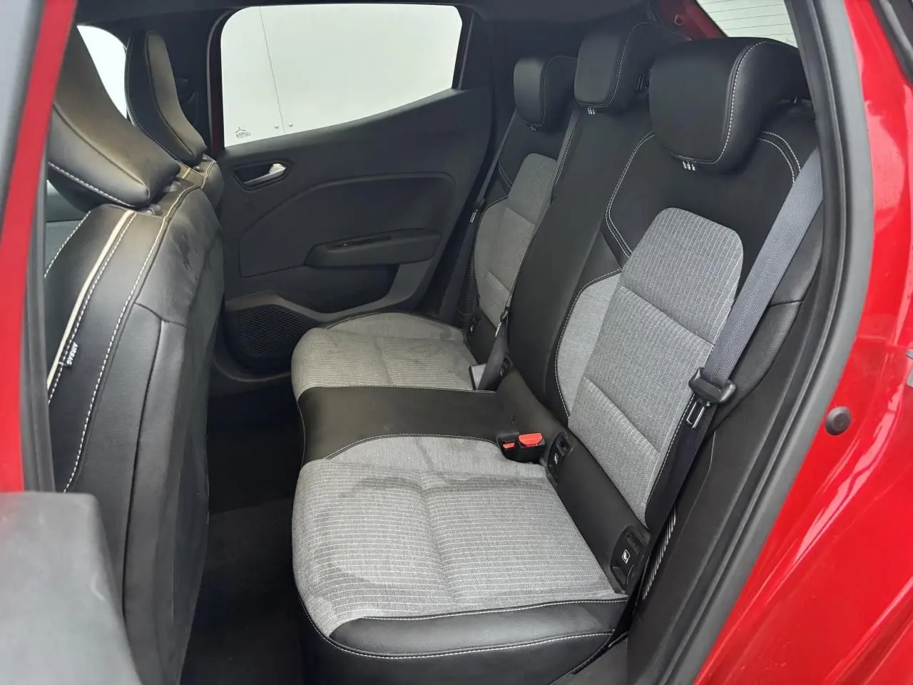 Vue côté droit de la banquette arrière grise et noire de la Renault Clio V rouge Flamme, avec ceinture et fixation ISOFIX visibles.