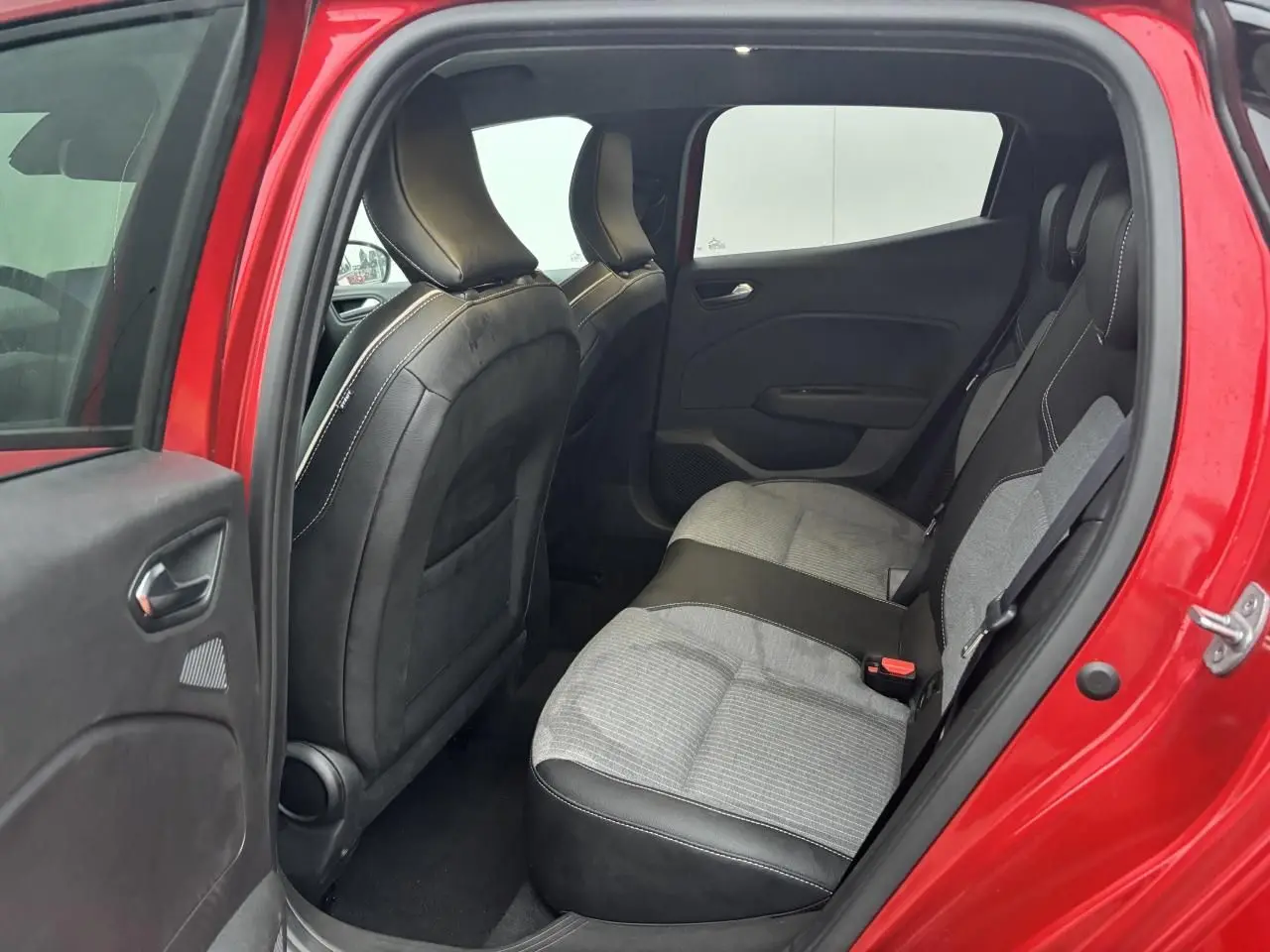 Vue intérieure côté gauche de la banquette arrière grise et noire d'une Renault Clio Rouge Flamme 2025 avec porte ouverte.