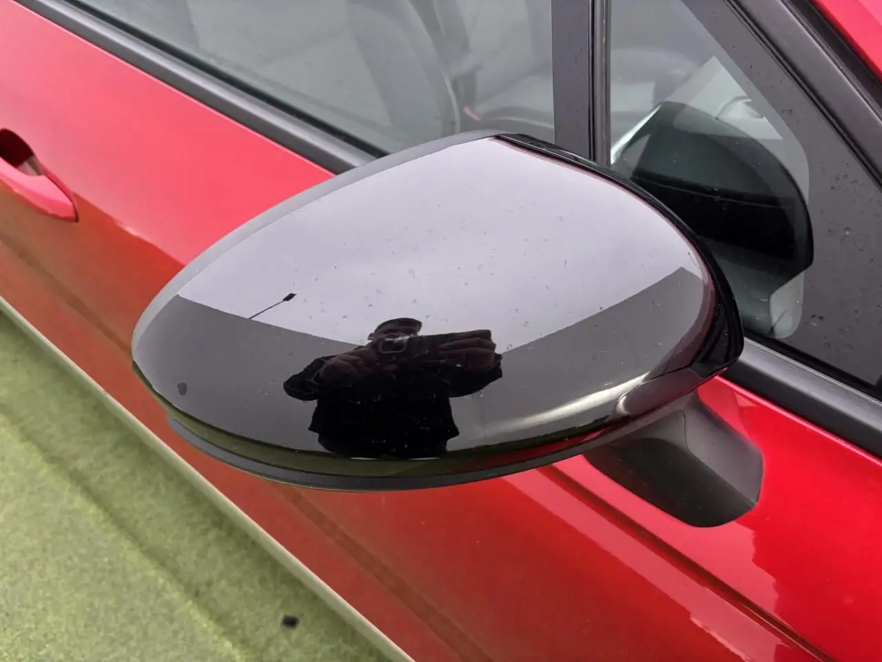 Rétroviseur extérieur noir brillant côté gauche sur porte rouge flamme d'une Renault Clio V hybride 2025.