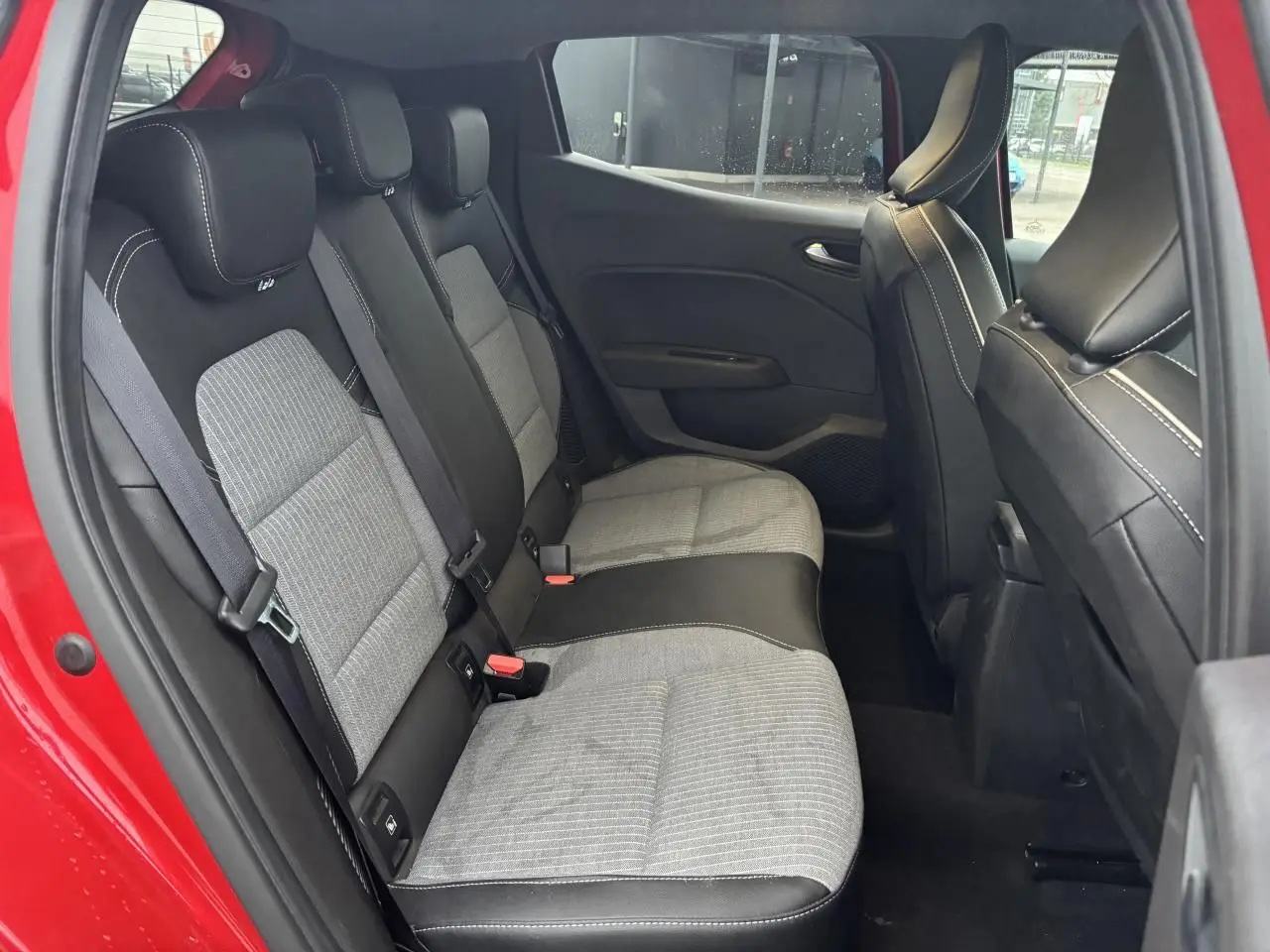 Vue intérieure côté gauche de la banquette arrière grise et noire d'une Renault Clio rouge flamme 2025.