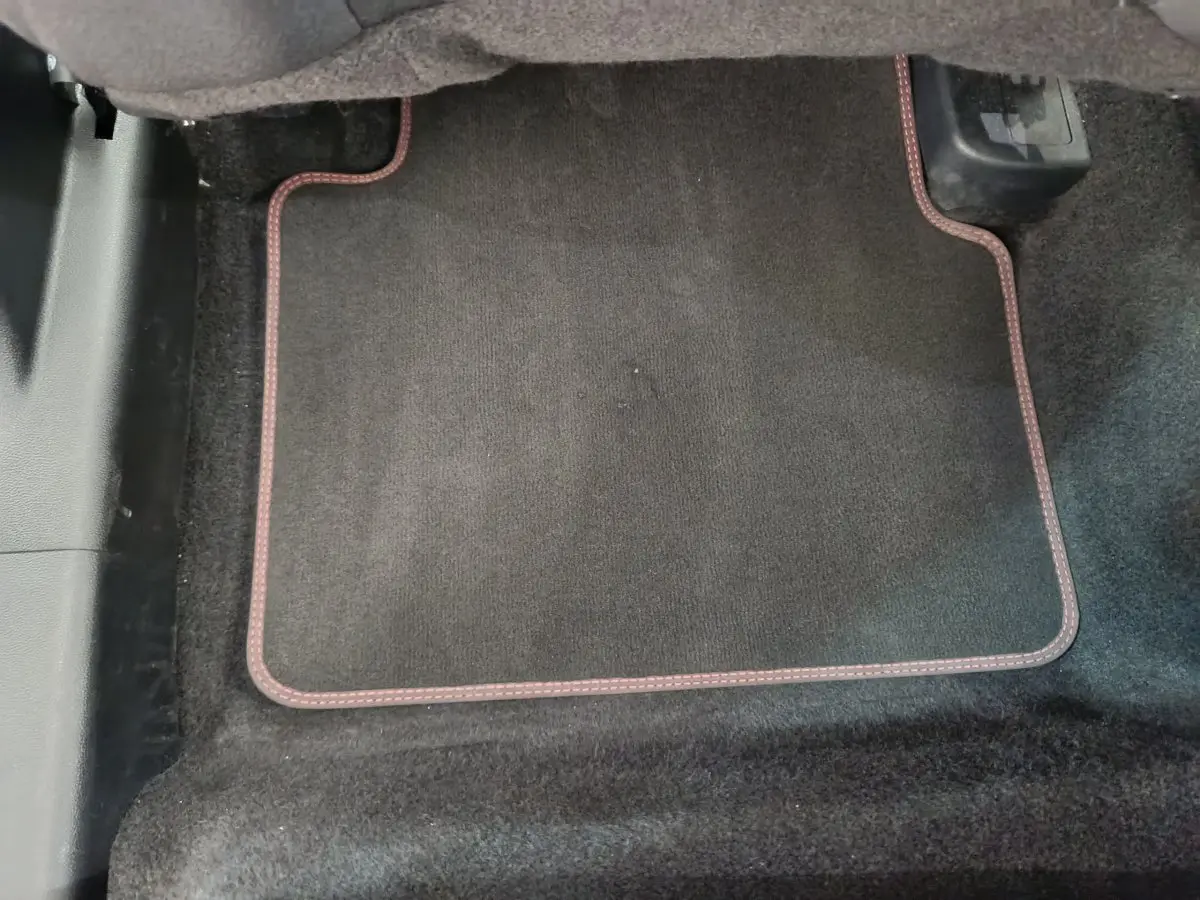 Tapis de sol noir avec surpiqûres rouges dans l'habitacle avant d'un Ford Kuga bleu 2024.