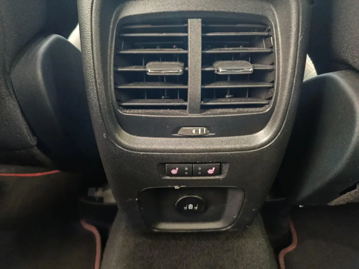Gros plan sur la console arrière noire du Ford Kuga bleu 2024 avec aérateurs, commandes chauffantes et prise USB.