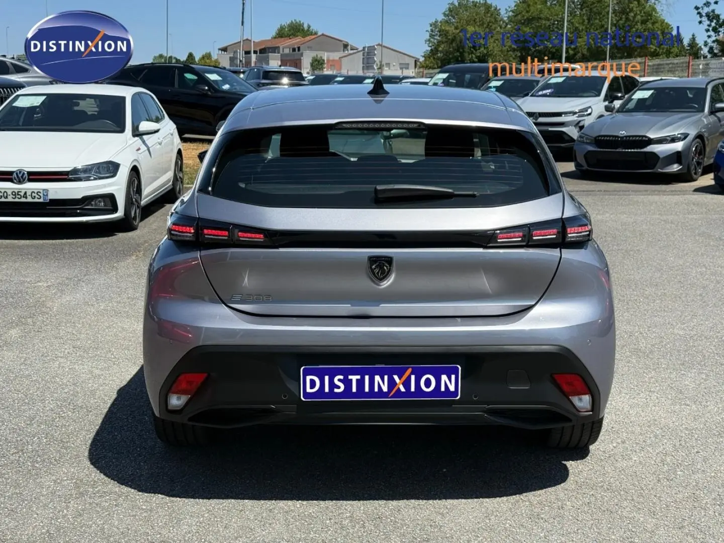Vue arrière d'une Peugeot e-308 gris Artense 2025 avec feux LED et logo lion distinctif sur parking.