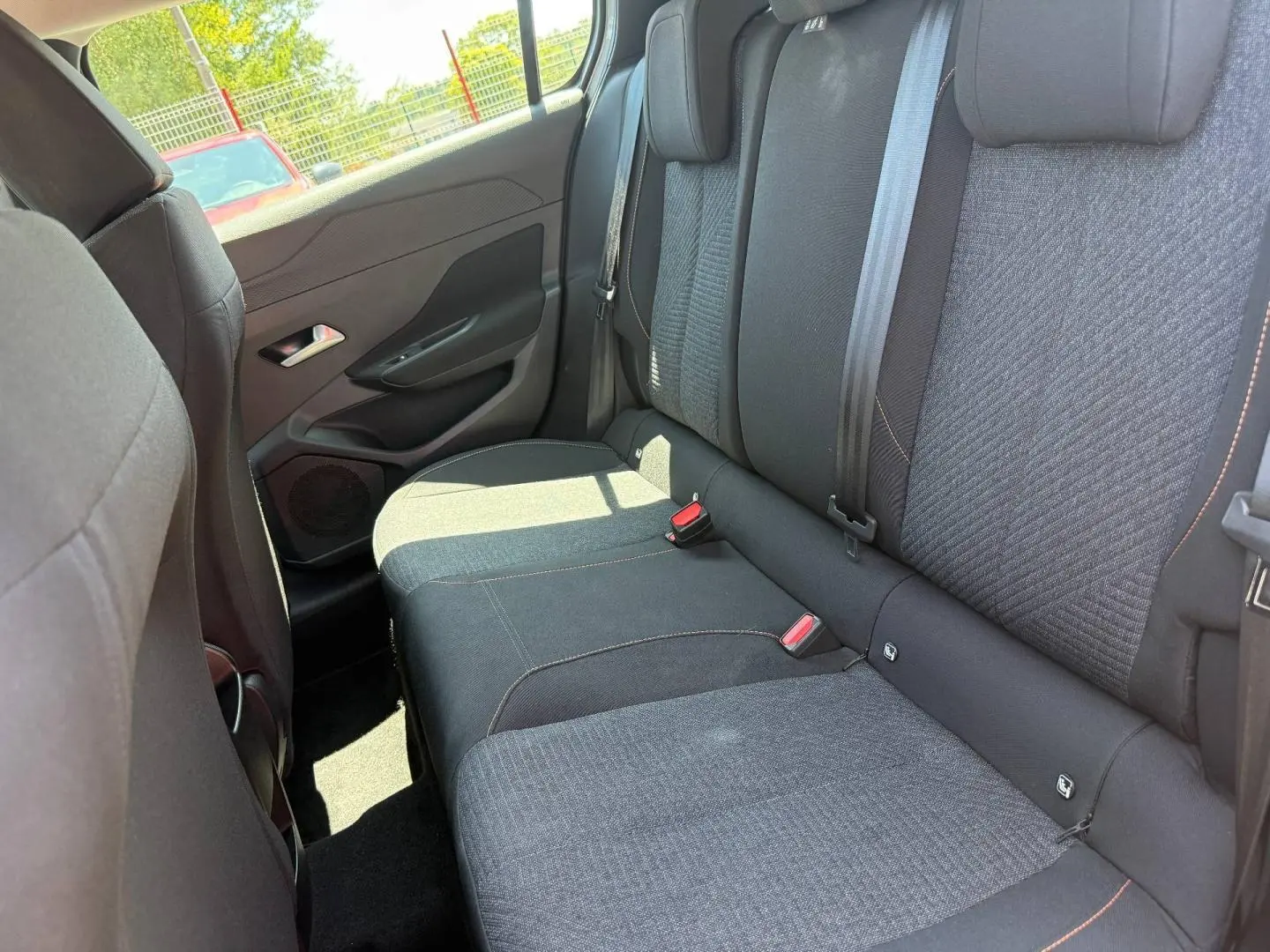 Vue intérieure côté gauche sur la banquette arrière tissu gris avec surpiqûres orange du Peugeot e-308 2025.