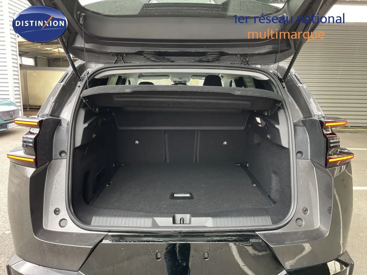 Vue arrière du coffre ouvert d'un Citroën C5 Aircross Hybrid gris platinium métal, avec feux arrière allumés en LED.