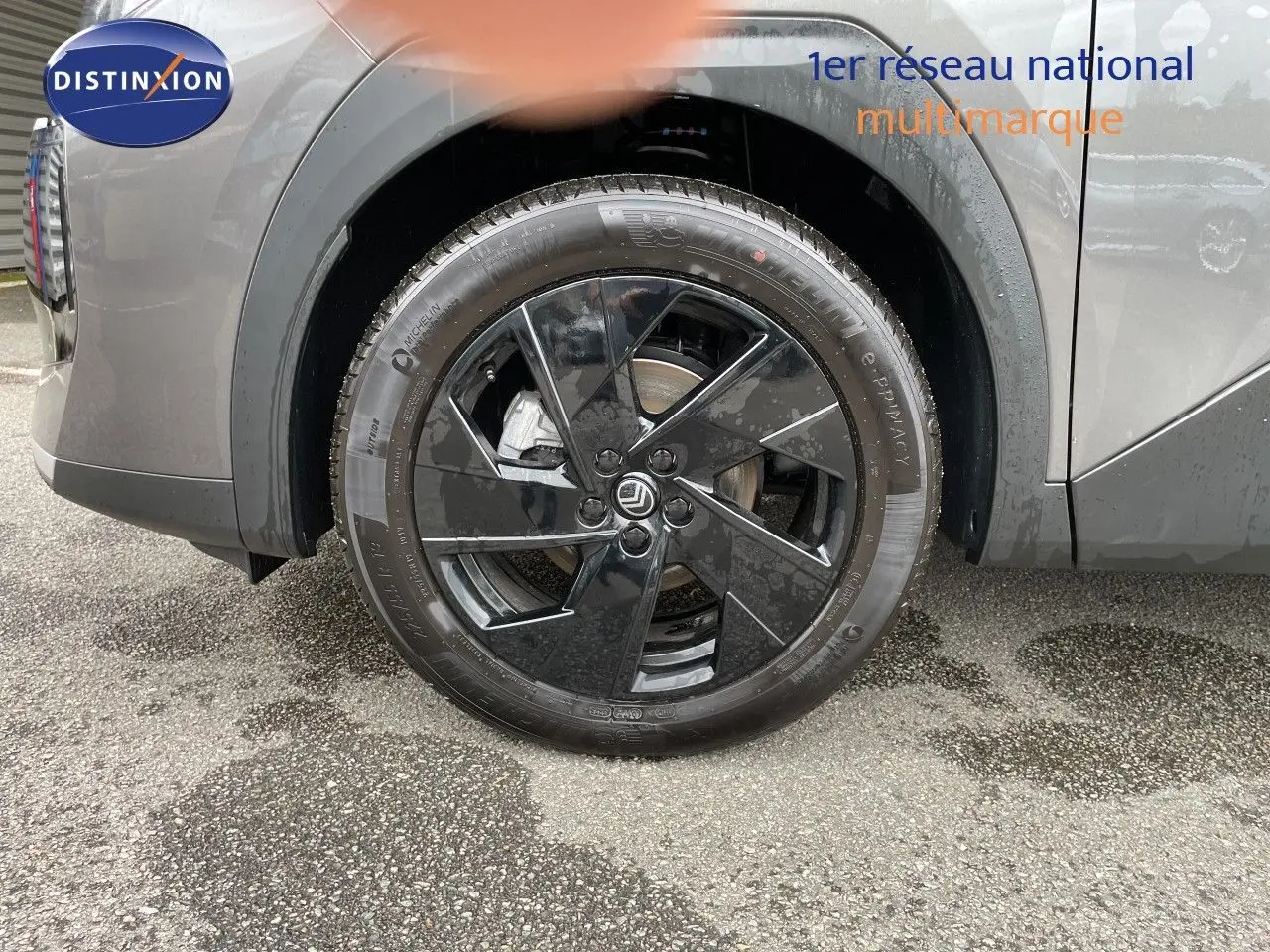 Gros plan sur la roue avant droite noire brillante d'un Citroën C5 Aircross gris platinium métallisé.