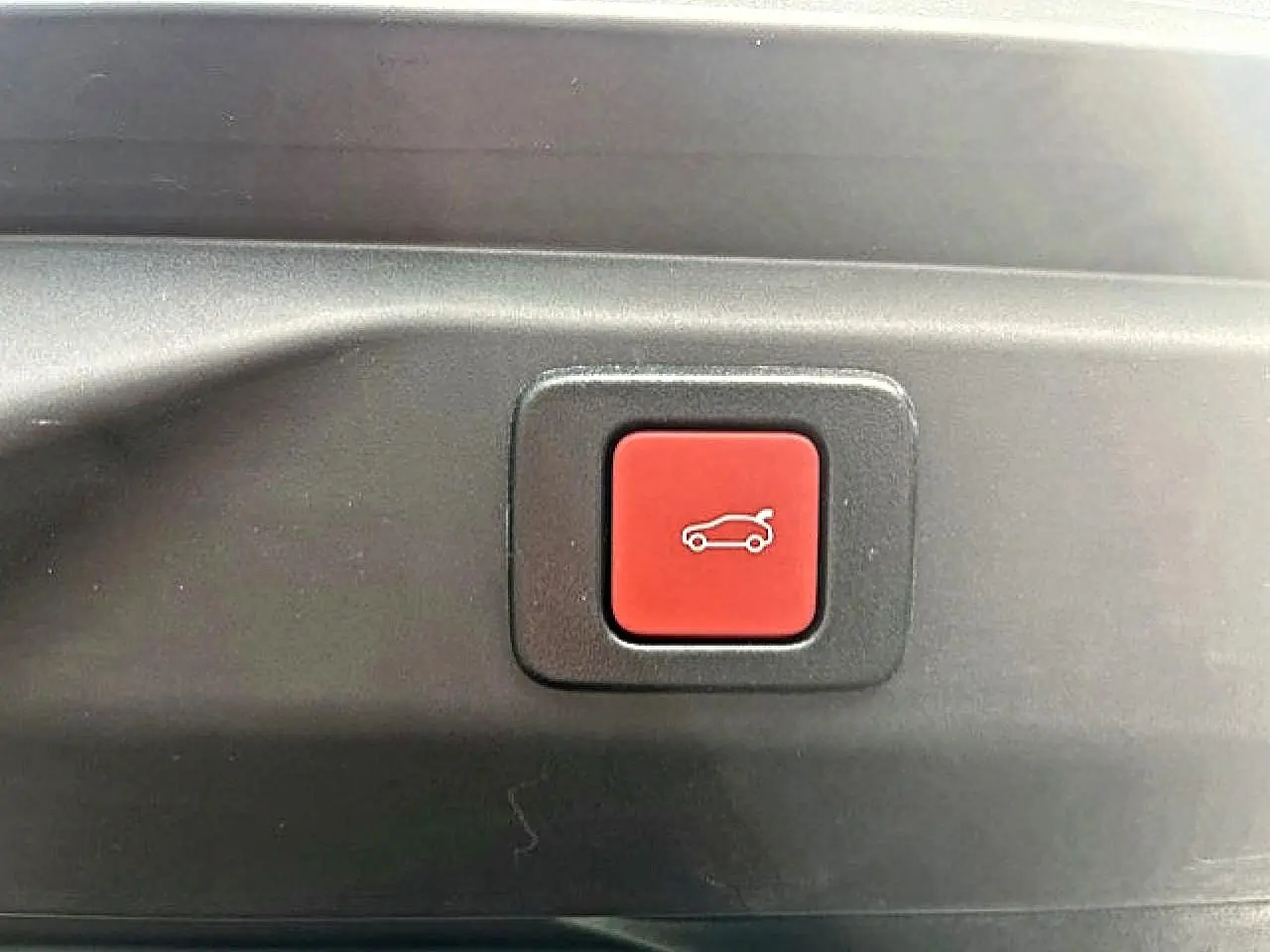 Bouton rouge d'ouverture électrique du coffre sur le hayon arrière du Peugeot 3008 gris Artense 2025.