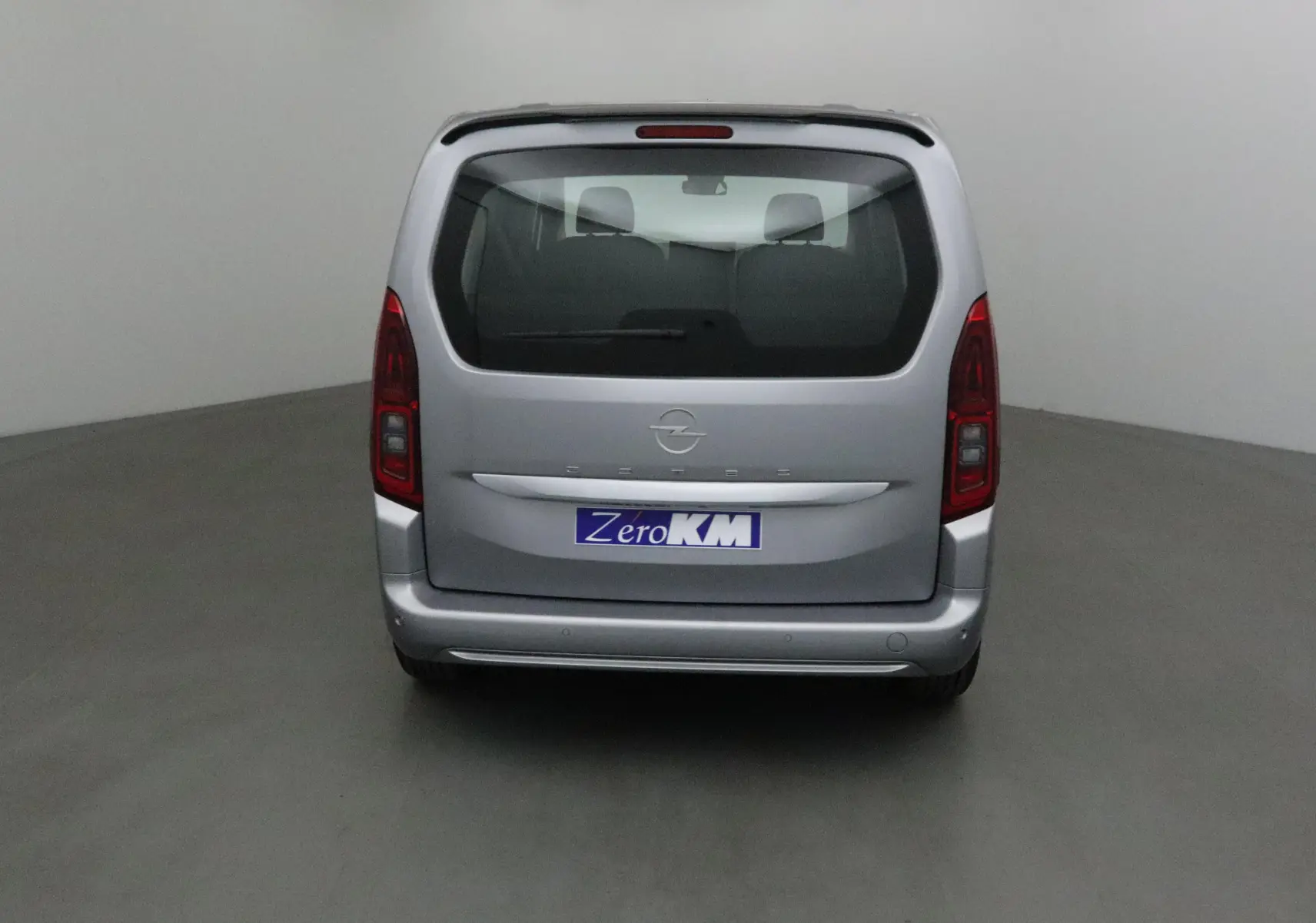 Vue arrière d'un Opel Combo Life gris Artense avec becquet et trois sièges individuels visibles à l'intérieur.