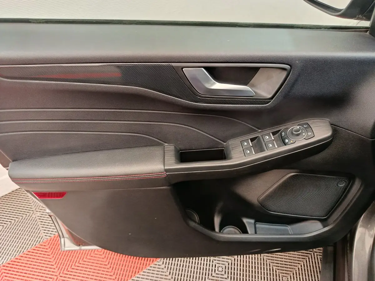 Panneau de porte avant gauche noir avec commandes électriques et accoudoir en cuir sur Ford Kuga gris clair 2024.
