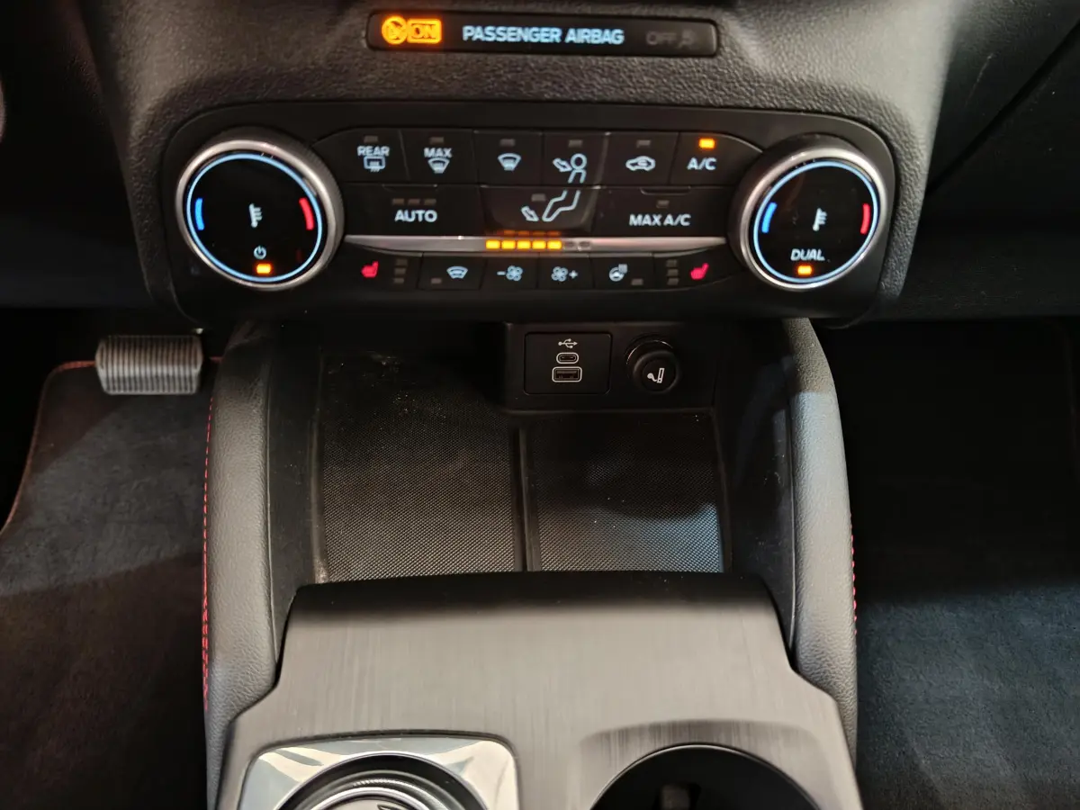 Vue rapprochée de la console centrale du Ford Kuga gris clair 2024, avec commandes climatisation et ports USB visibles.