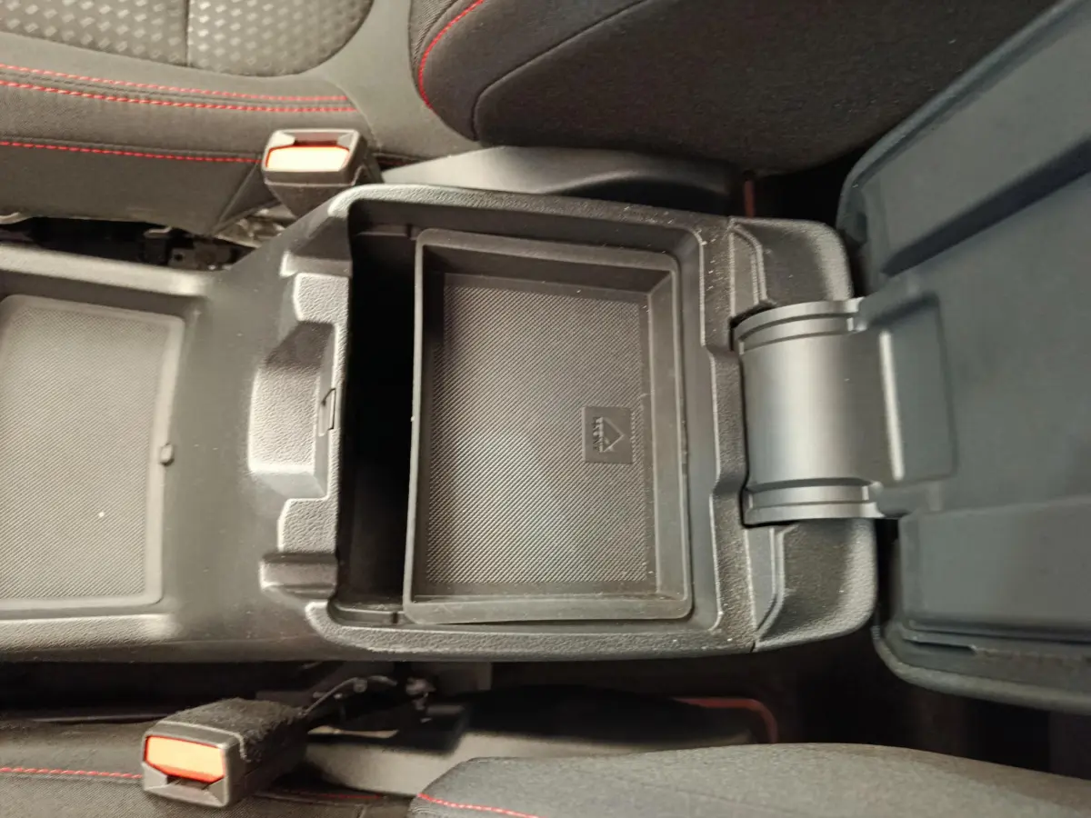 Vue plongeante sur le rangement central ouvert du Ford Kuga gris clair, avec surpiqûres rouges visibles sur les sièges noirs.