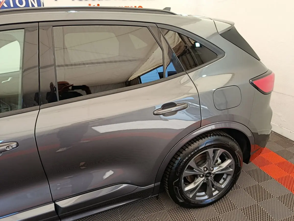 Vue côté droit arrière du Ford Kuga 2024 gris clair, mettant en valeur la porte arrière et la roue alliage.