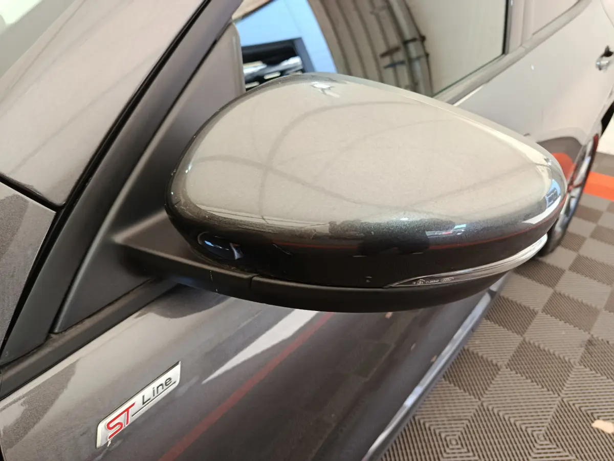 Gros plan sur le rétroviseur côté gauche gris clair du Ford Kuga 2024 version ST Line avec logo ST visible sur la portière.