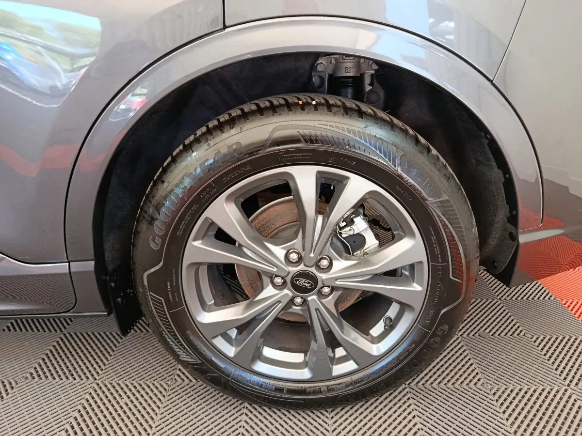 Gros plan sur la roue avant gauche du Ford Kuga gris clair 2024 avec jante alliage et pneu Goodyear.