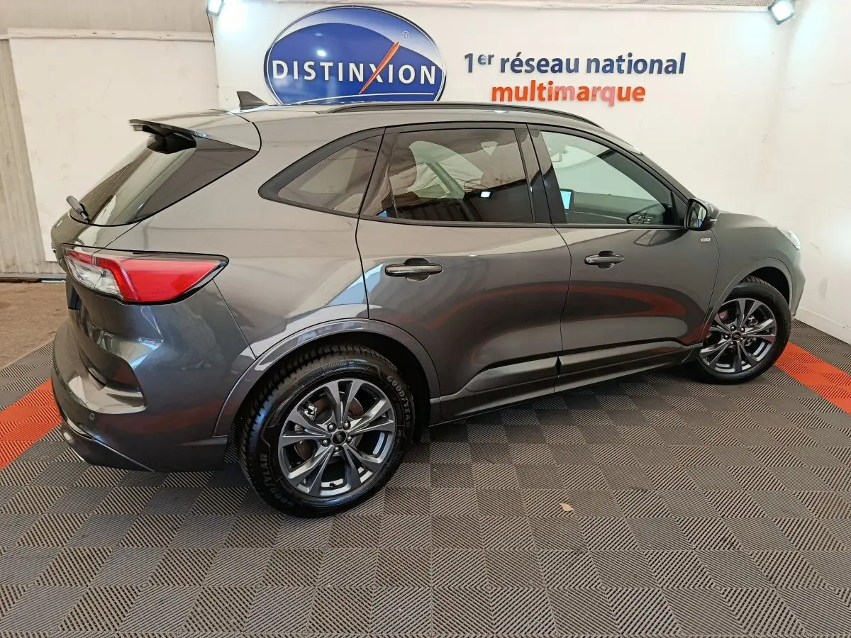 Ford Kuga 2024 gris clair vue de profil côté droit, avec jantes alliage et vitres teintées dans un showroom