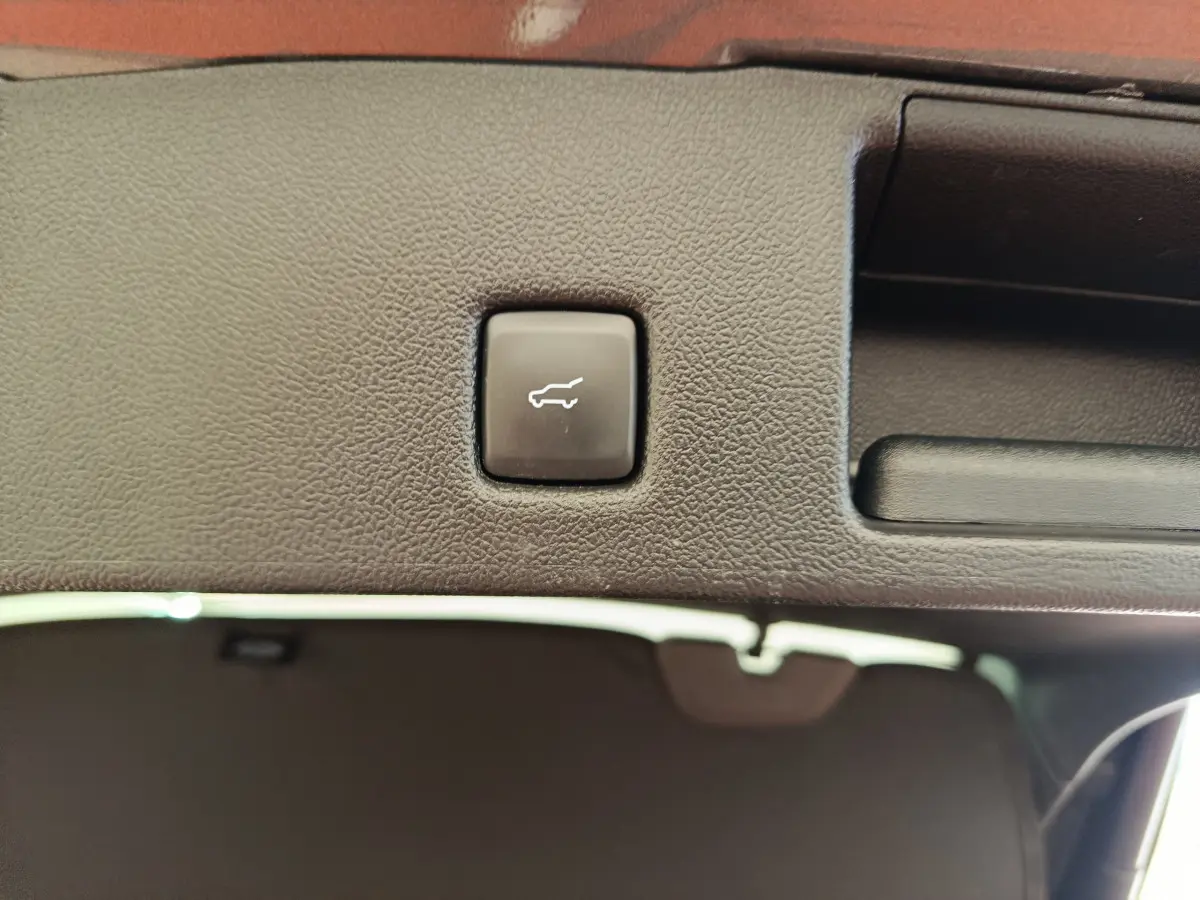 Bouton d'ouverture électrique du coffre sur la garniture intérieure arrière du Ford Kuga gris clair 2024.