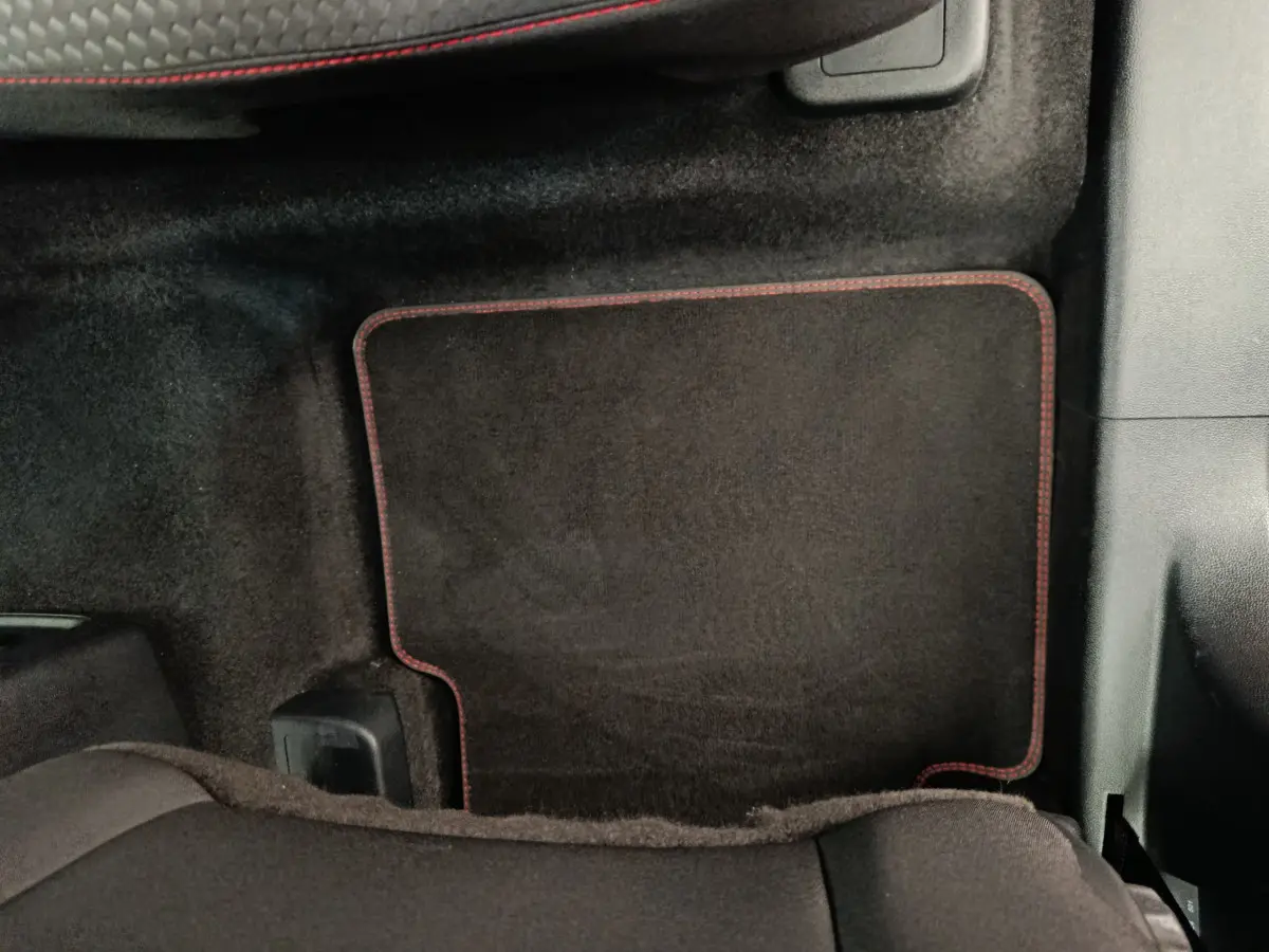 Tapis de sol noir avec surpiqûres rouges côté passager arrière d'un Ford Kuga 2024 gris clair St Line.