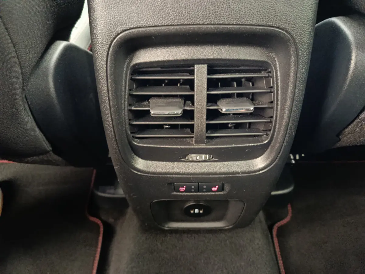 Gros plan sur la console arrière noire du Ford Kuga 2024 avec aérateurs, commandes de sièges chauffants et prise USB.