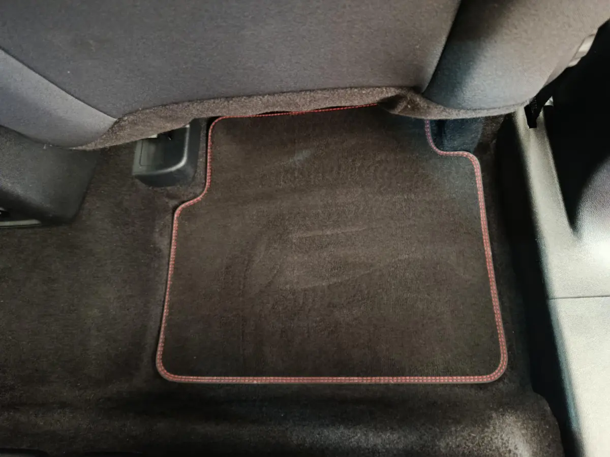 Tapis de sol noir avec surpiqûres rouges sous le siège arrière du Ford Kuga gris clair 2024 St Line.